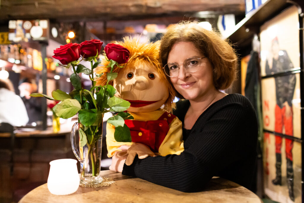 Eine Frau mit einer Therapiepuppe, daneben ein Strauß Rosen